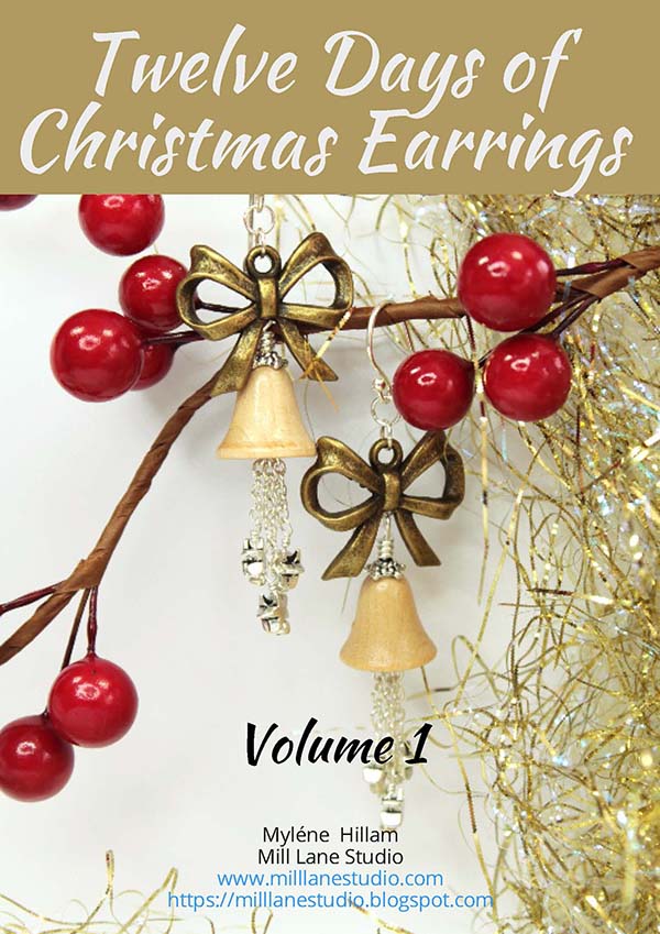 Scandinavian style Christmas earrings featuring bronze bows and wooden bells with dangling chains, hanging from a twiggy branch from a Christmas garland