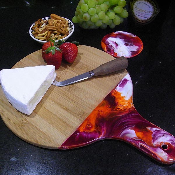 Burgundy and orange resin cheese board with cheese, fruit and nuts